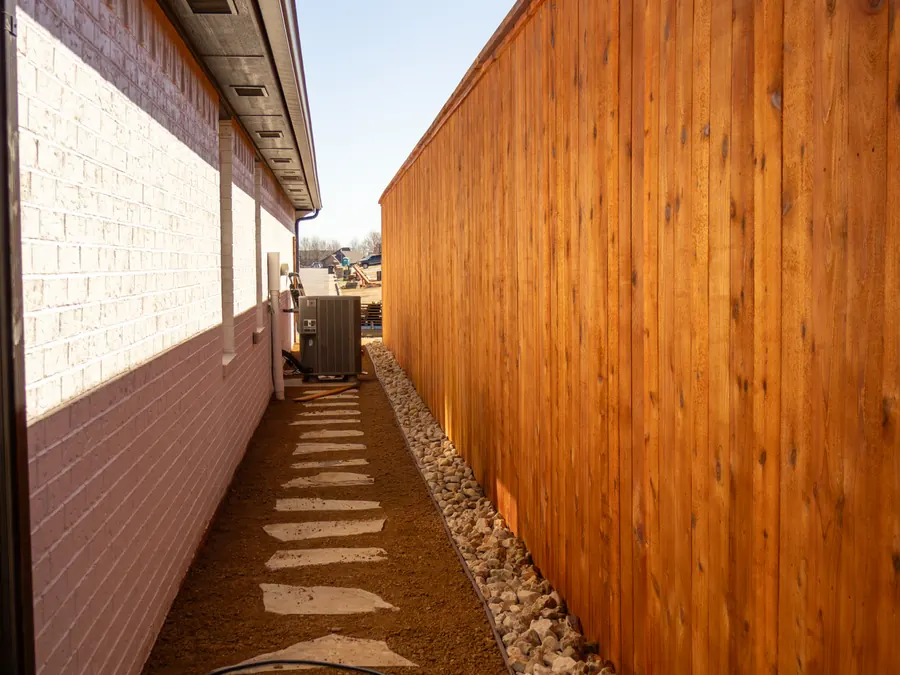 New stained cedar privacy fence with rock border